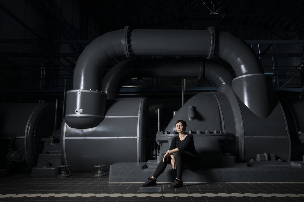 Dr Agata Zysiak sitting in front of a turbine casing in the historic EC-1 power plant in Łódź. Photo by Dr Bartosz Kałużny.
