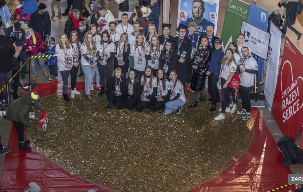 The University of Lodz students standing next to a huge heart made of gold coins 