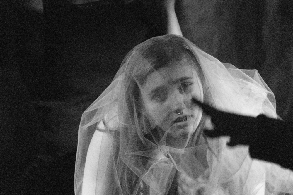A still from the performance, a black and white photograph, a woman in a wedding dress looking straight ahead