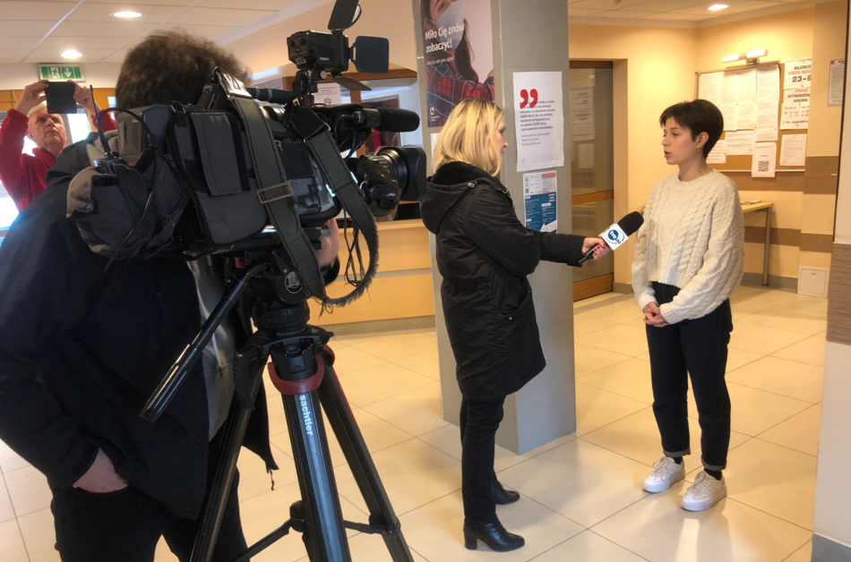 ekipa telewizyjna z kamerą rozmawia z młodą kobietą