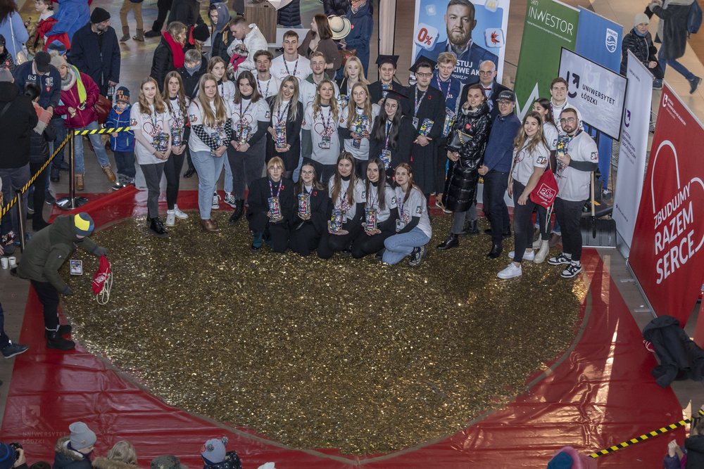 The University of Lodz students from the Student Science Club Inwestor standing with the University of Lodz authorities next to a heart made of gold coins