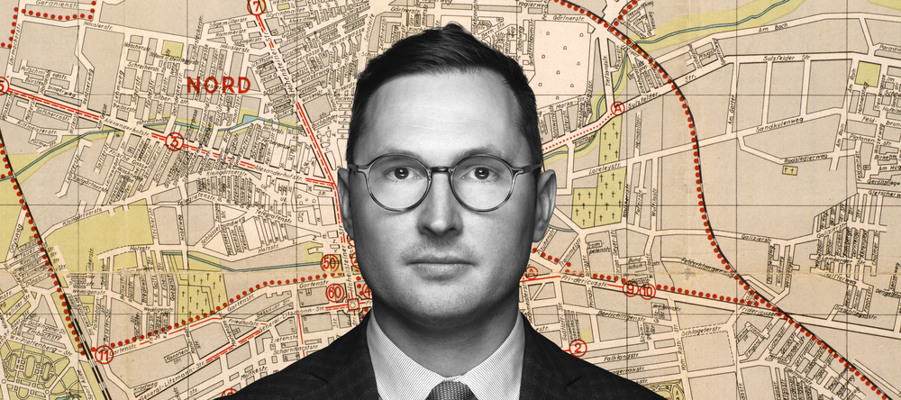 Dr Adam Sitarek on the background of a fragment of the map of the Lodz ghetto